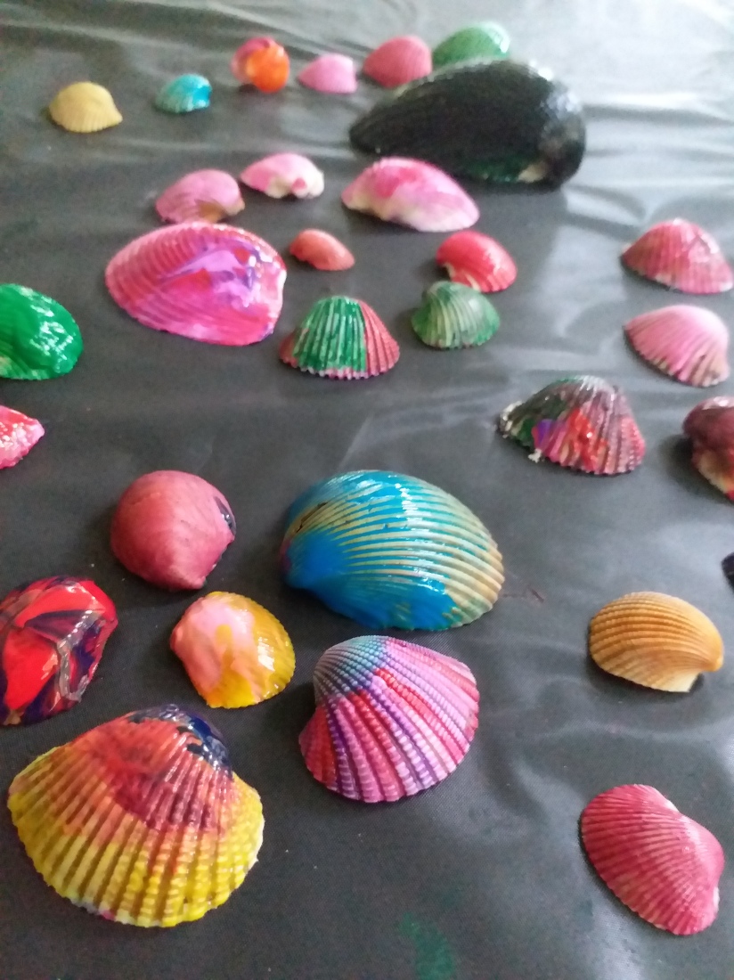 a number of painted cockel shells arranged in circles of 5 or 6 with one in the middle. 